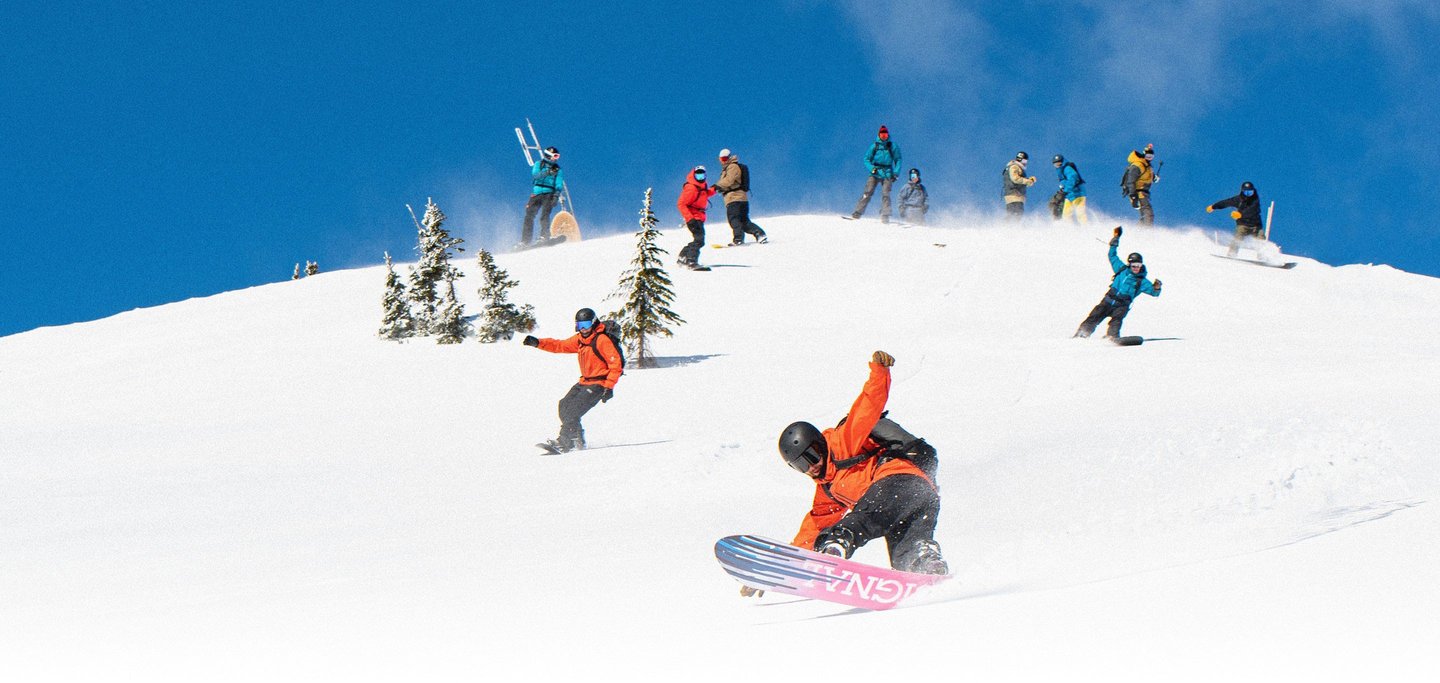 Snowboarders traveling down a snowy mountain