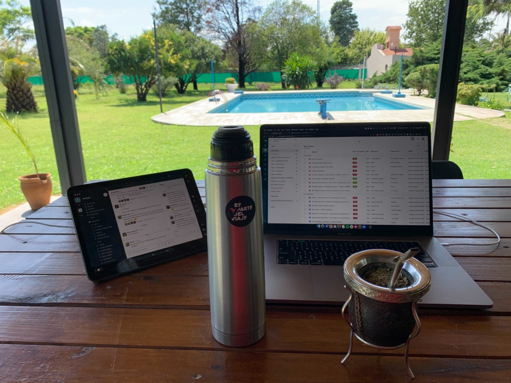 Remote work as shown by a laptop in someone's backyard with a pool.