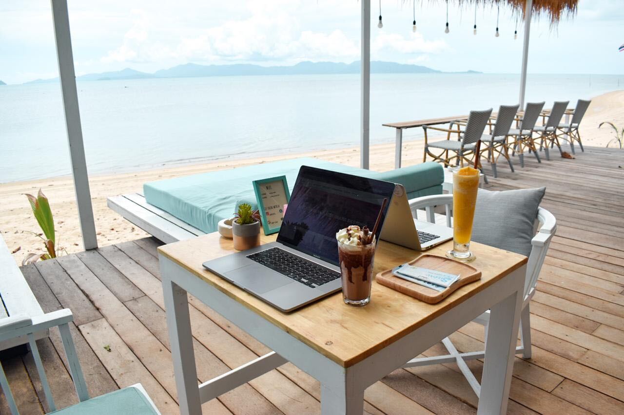 Remote work as shown by a laptop at a cabana on the beach.