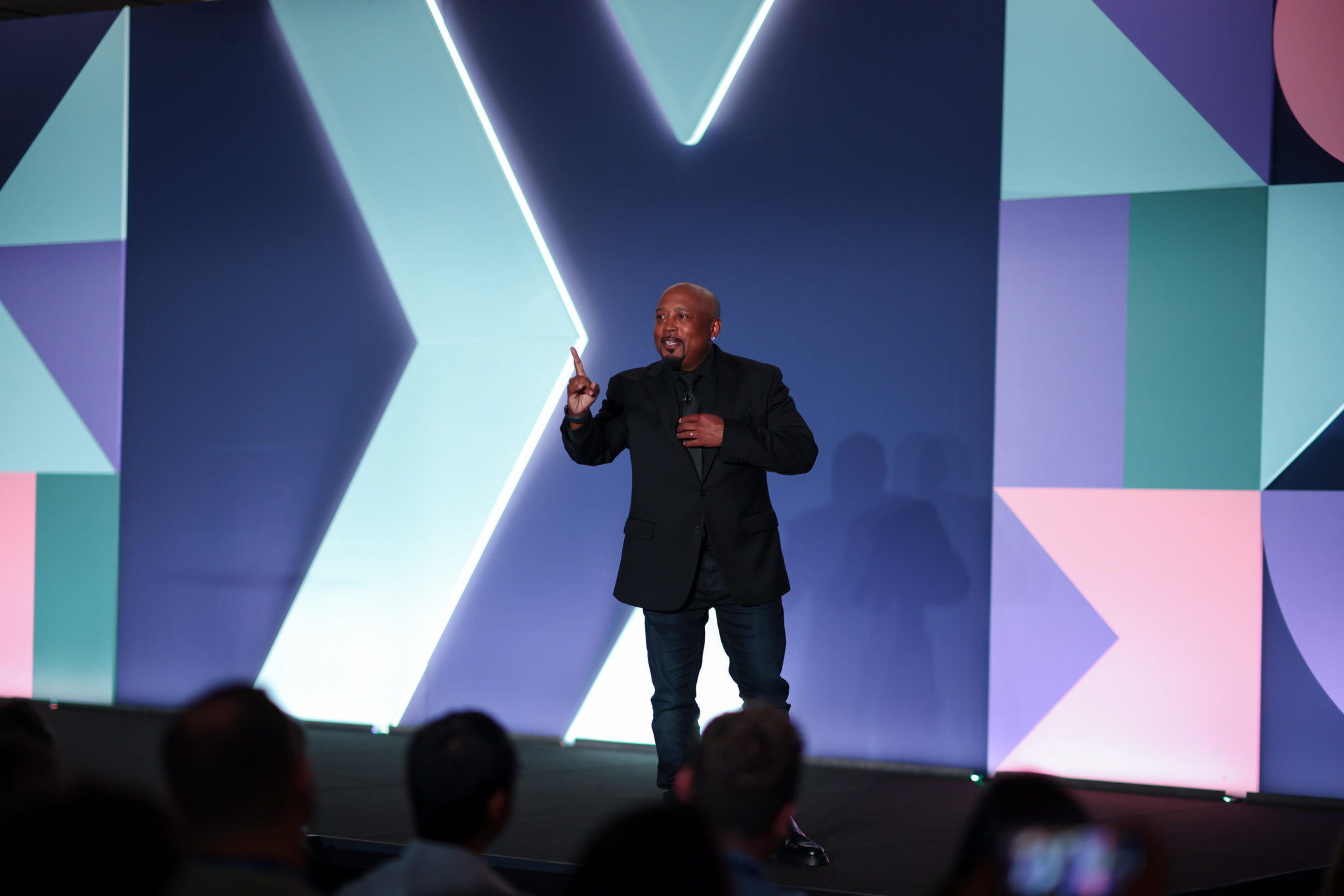 Daymond John standing on stage presenting to the audience in front of the ChargeX branding.