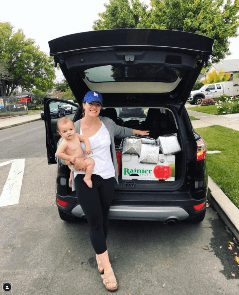 Bumpin Blends founder, Lisa Mastela and her newborn baby posing outside their car with a trunk load of subscription order smoothies filling up that back waiting to be delivered.