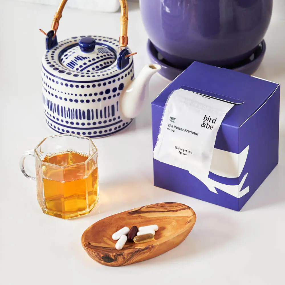 An arrangement of Bird&Be products, featuring a cup of tea and prenatal vitamins