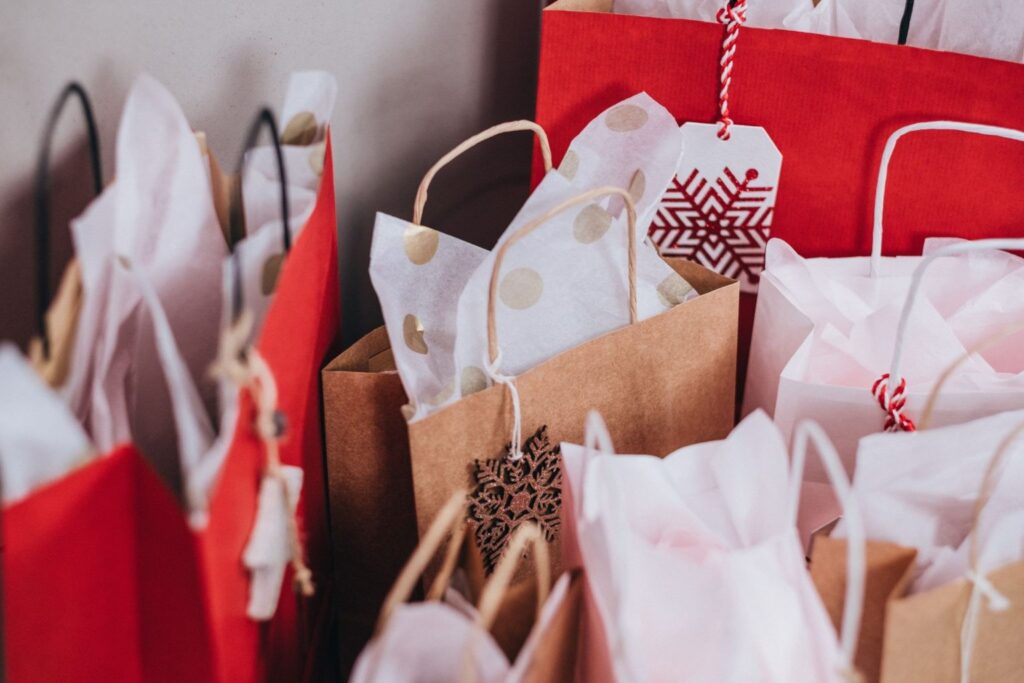 Assorted red and brown holiday gift bags with white tissue paper